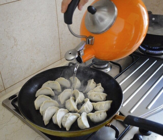 adding water to pan of dumplings