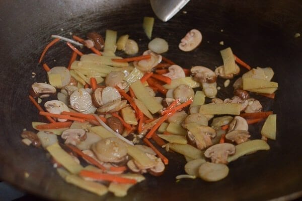 Take the shrimp and noodles out of the refrigerator, and let them come up to room temperature. One trick for the noodles is to soak the whole bag (unopened) in hot water, which speeds up the warming process without making the noodles soggy. If you can’t find lo mein noodles, you can actually substitute dried linguini. Just cook until al dente, drain, and immediately toss with 1 tablespoon of vegetable oil, working the oil into the pasta so the noodles don't stick together. Always prepare your noodles just before you are ready to make the dish, so they don’t dry out and remain at room temperature or warmer. This makes the stir-frying process much easier. Combine the sugar, soy sauces, oyster sauce, sesame oil, and white pepper in a bowl until the sugar is dissolved and set aside. Heat a large wok over high heat until it just starts to smoke, and add 1 tablespoon of oil around the perimeter of the wok. Quickly spread the shrimp around your wok and let them sear for 10-15 seconds on each side. Immediately transfer the shrimp to a plate and set aside. Return the wok to the highest heat possible and add 2 tablespoons oil, along with the garlic. After a few seconds, add the mushrooms, carrots, bamboo shoots, and water chestnuts and stir-fry for 30 seconds. Next, spread the Shaoxing wine around the perimeter of the wok, and then add the napa cabbage. Stir-fry for another 30 seconds. Spread the noodles evenly over the vegetables and give everything a good stir for 1 minute. Now, you can see why you want everything at room temperature, or everything will be overcooked and mushy by the time it heats up! At this point, the noodles should be softened, so add in the sauce mixture you set aside earlier and mix until everything is well combined. Stir-fry for another 30 seconds using a scooping motion, until the sauce is well distributed. Add in the shrimp, snow peas, bean sprouts, and scallions. Mix well for another 2 minutes and serve!