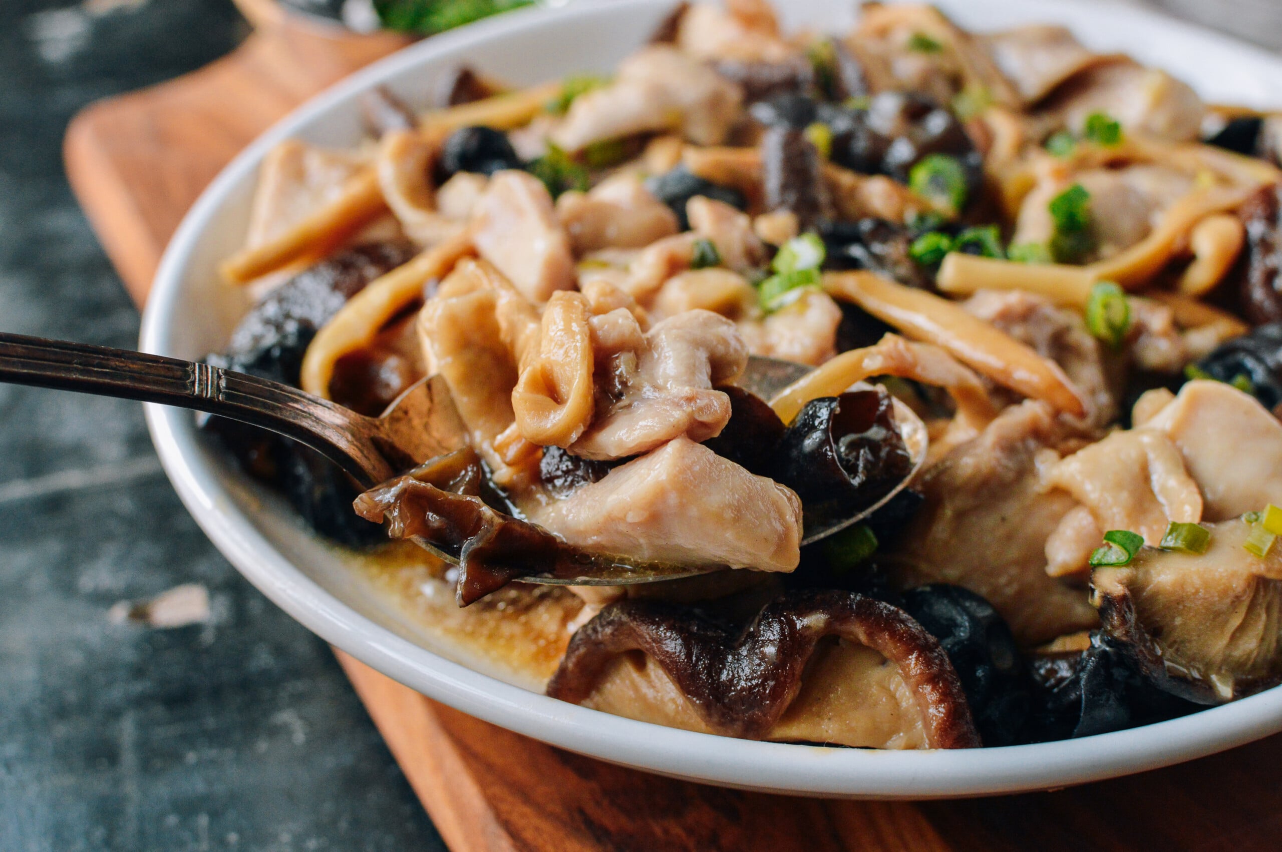Scooping steamed chicken with lily flowers and dried mushrooms with a spoon