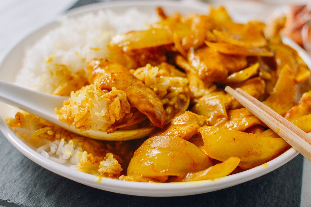 eating stir-fried curry chicken with rice using chinese soup spoon and chopsticks