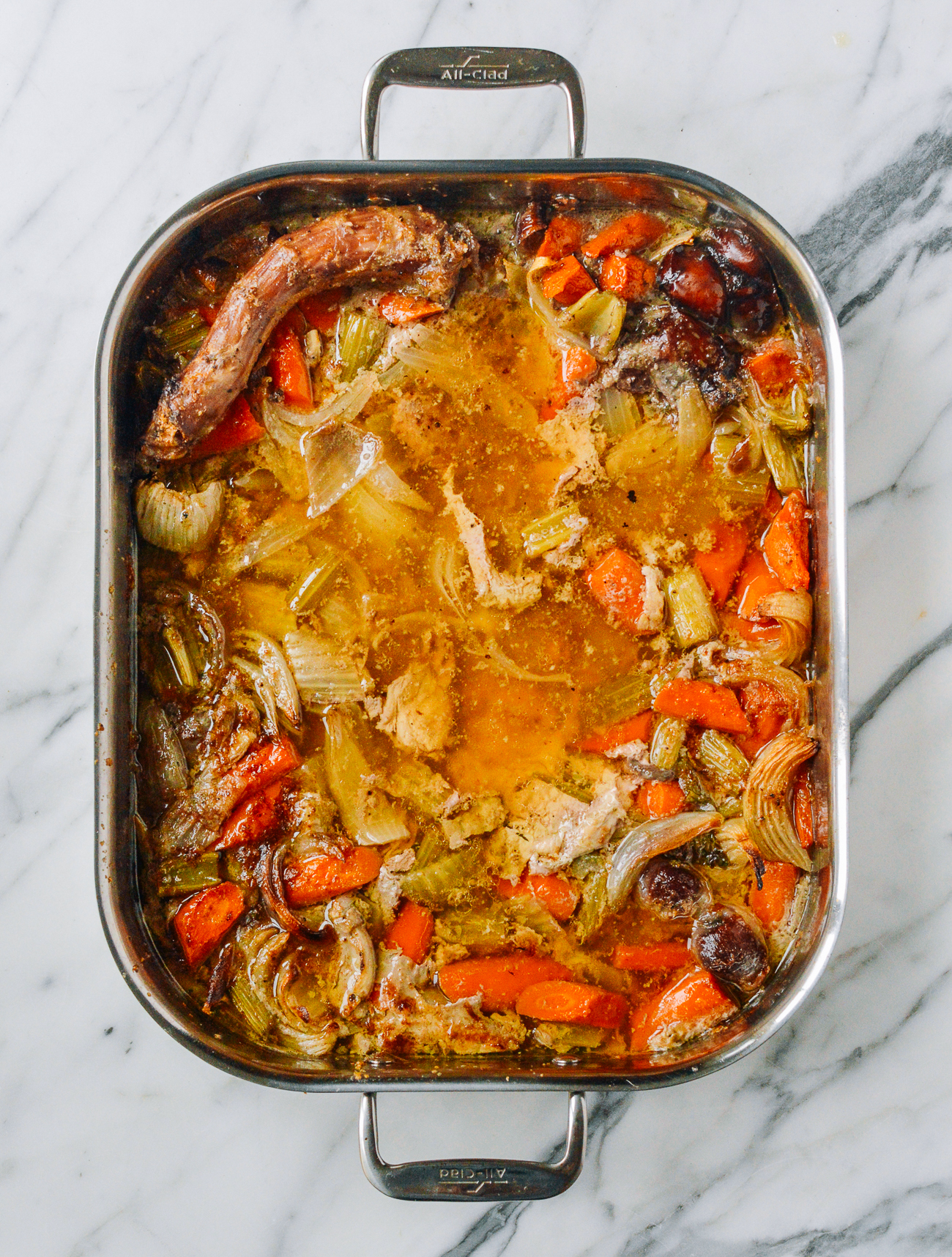 vegetables, juices, and turkey neck in roasting pan after roasting turkey
