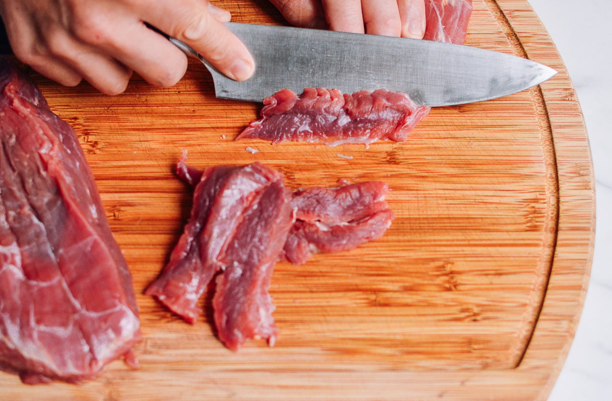 slicing beef flank steak on a cutting board by jcghk.dfhdjkvfj.cf