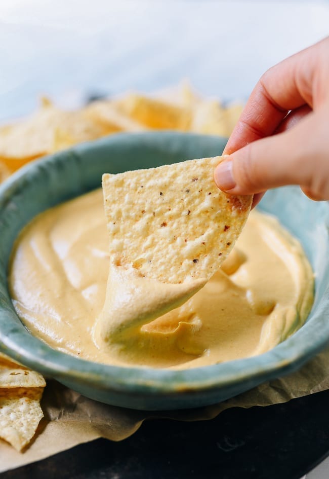 Dipping tortilla chip into plain vegan queso, jcghk.dfhdjkvfj.cf