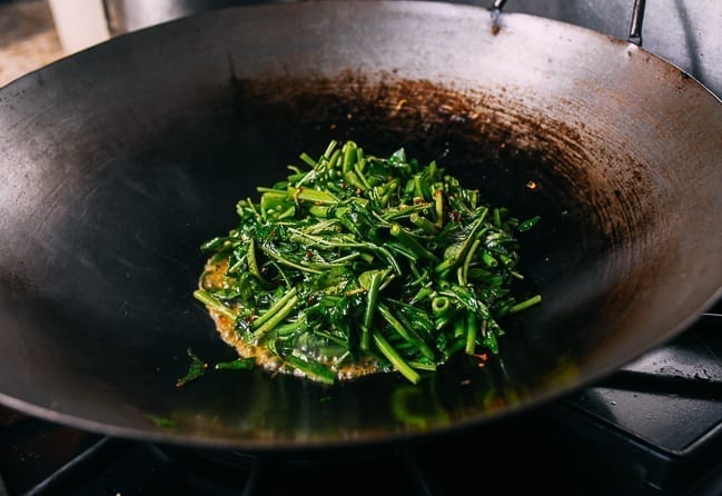 Piling water spinach in center of wok