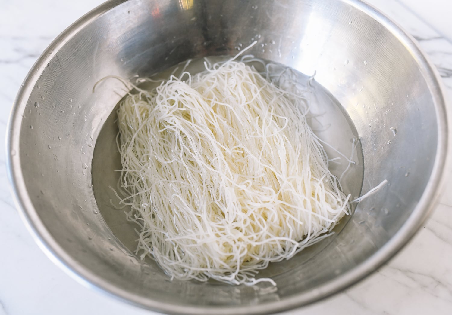 Soaking rice noodles in water in metal bowl, jcghk.dfhdjkvfj.cf