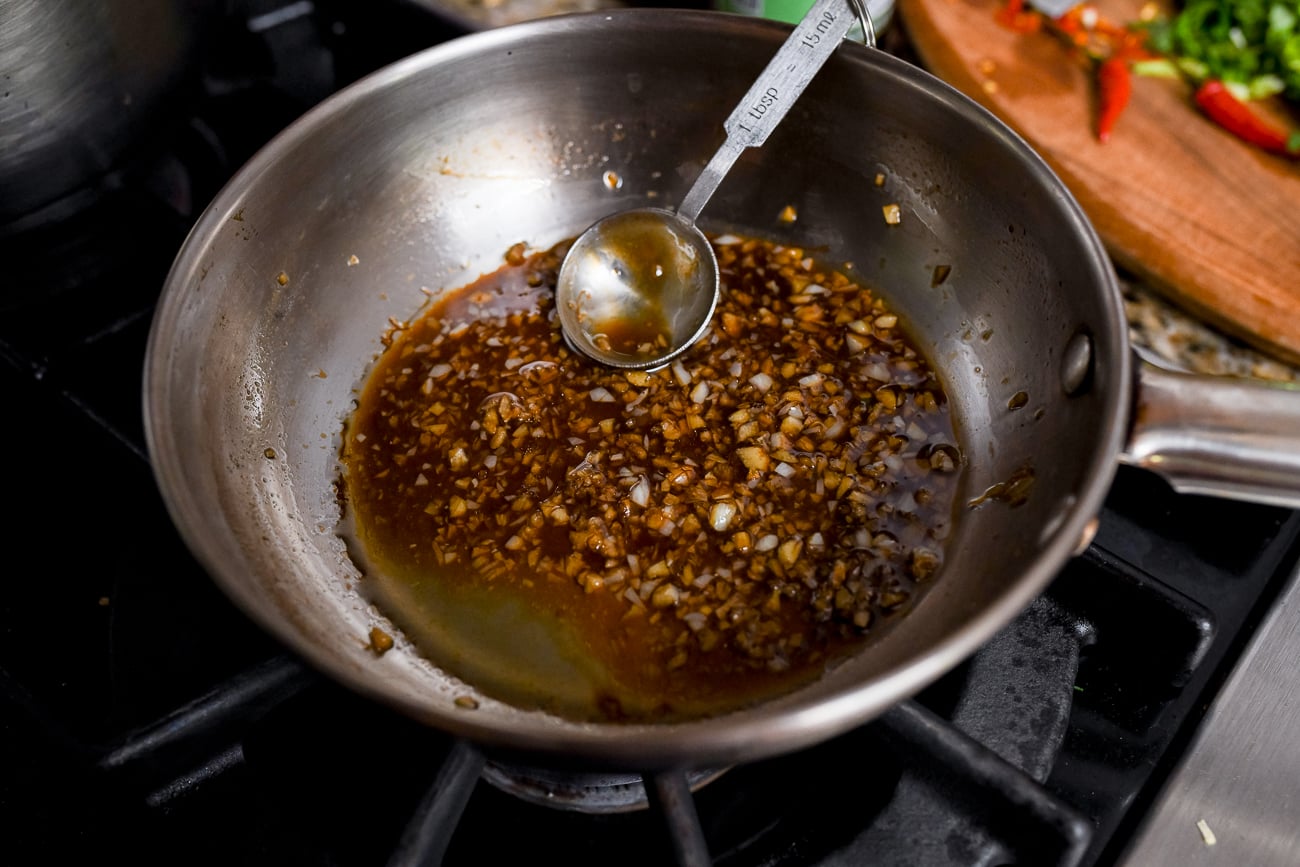 Stirring sauce with measuring spoon in saucepan