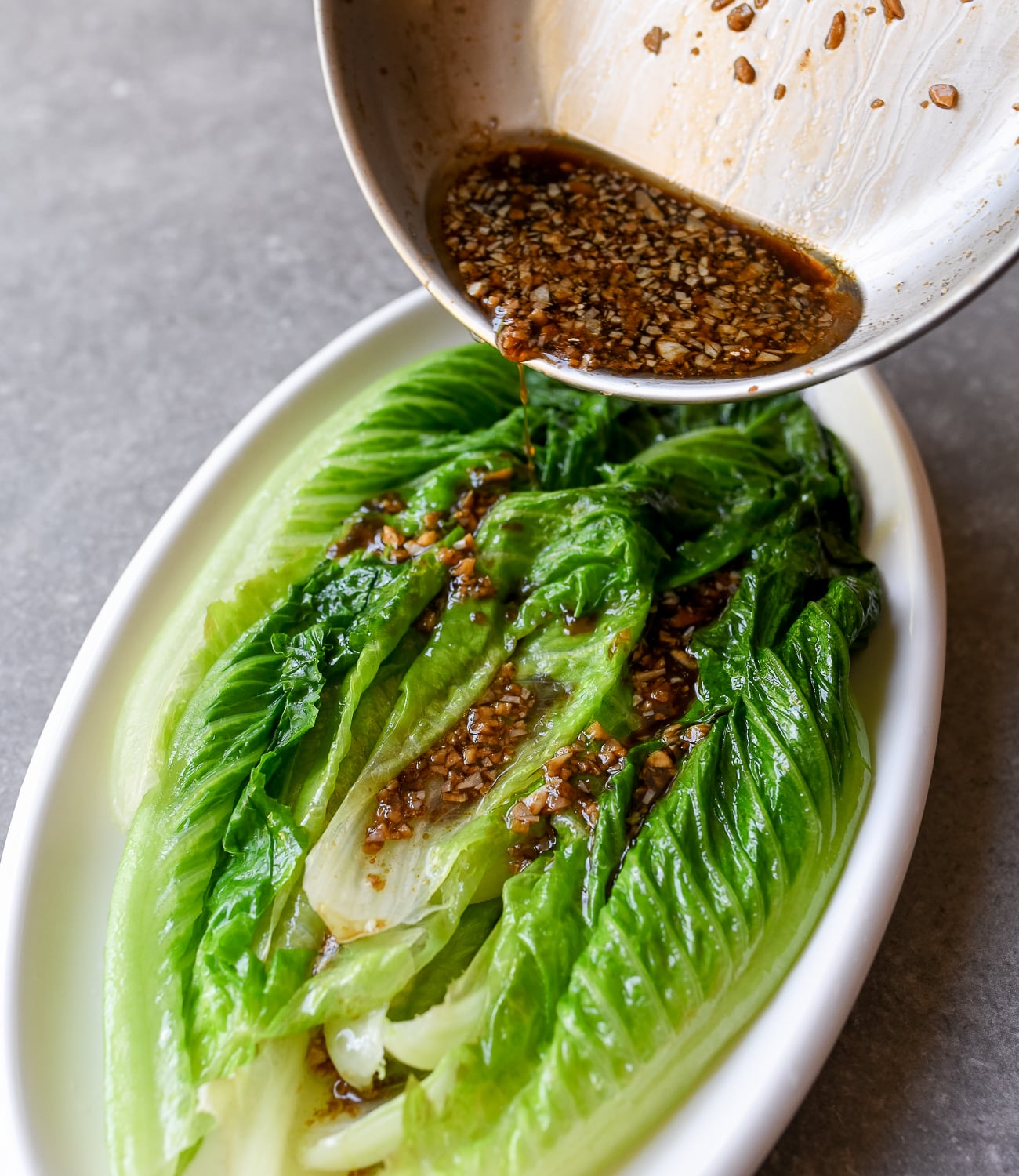 Pouring sauce over blanched romaine lettuce leaves