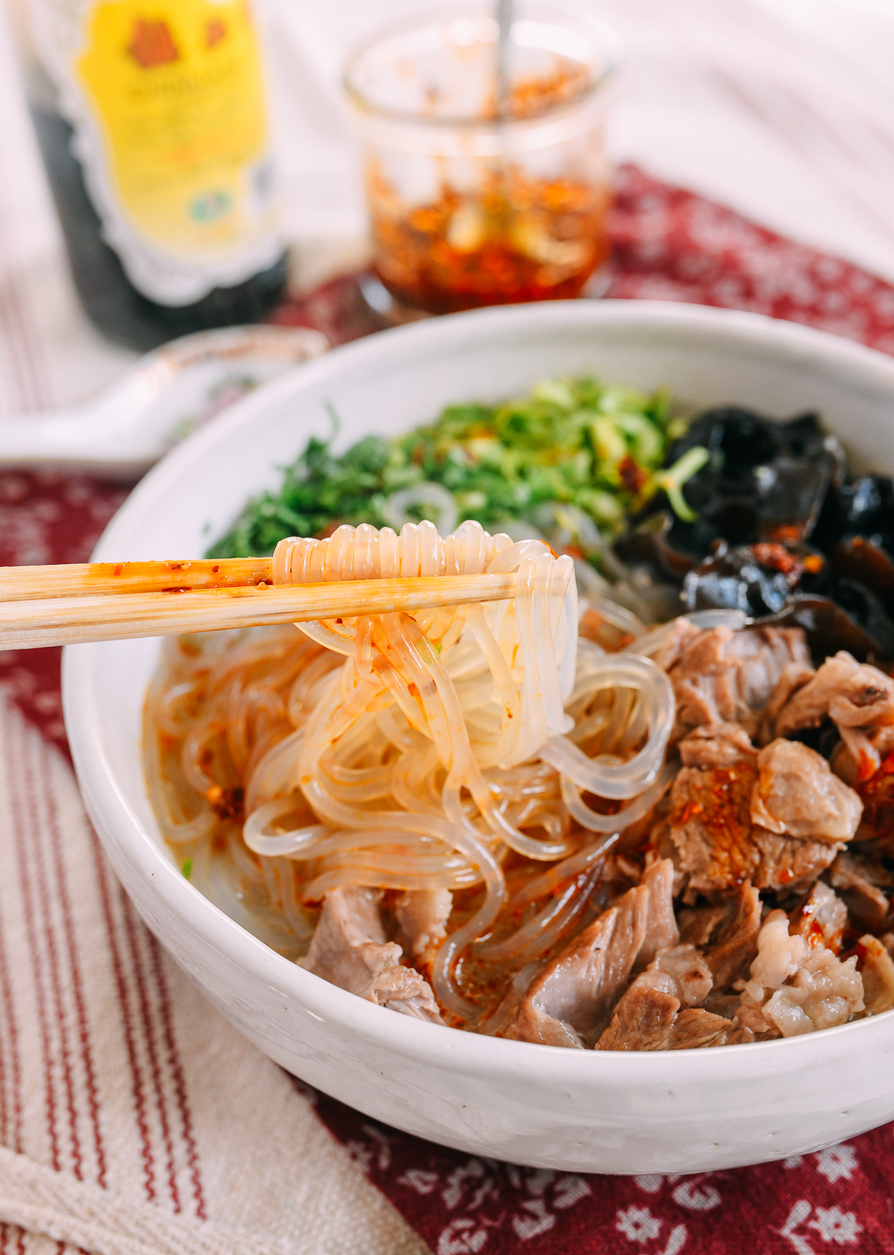 Picking up glass noodles with chopsticks from bowl of lamb noodle soup