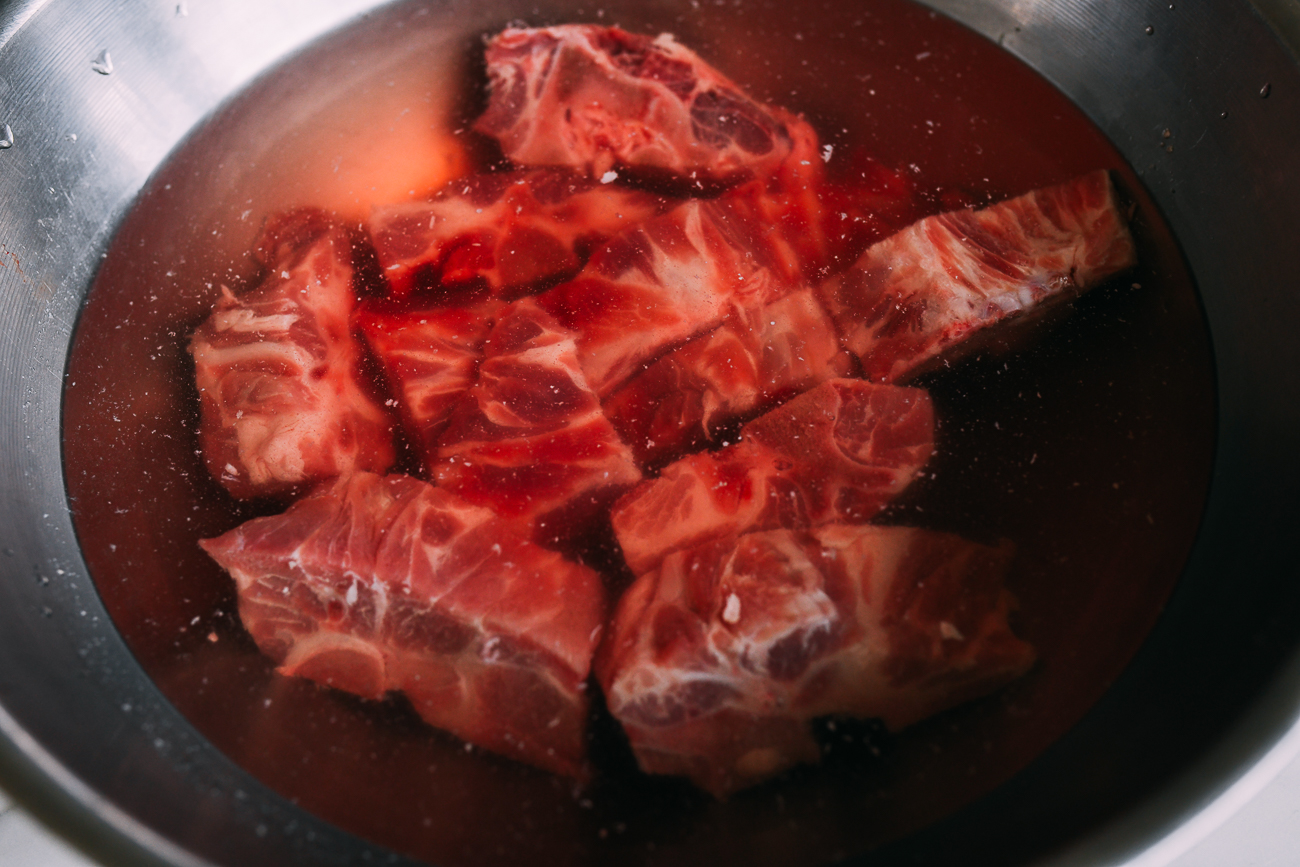 Soaking pork neck bones in water in a large metal bowl