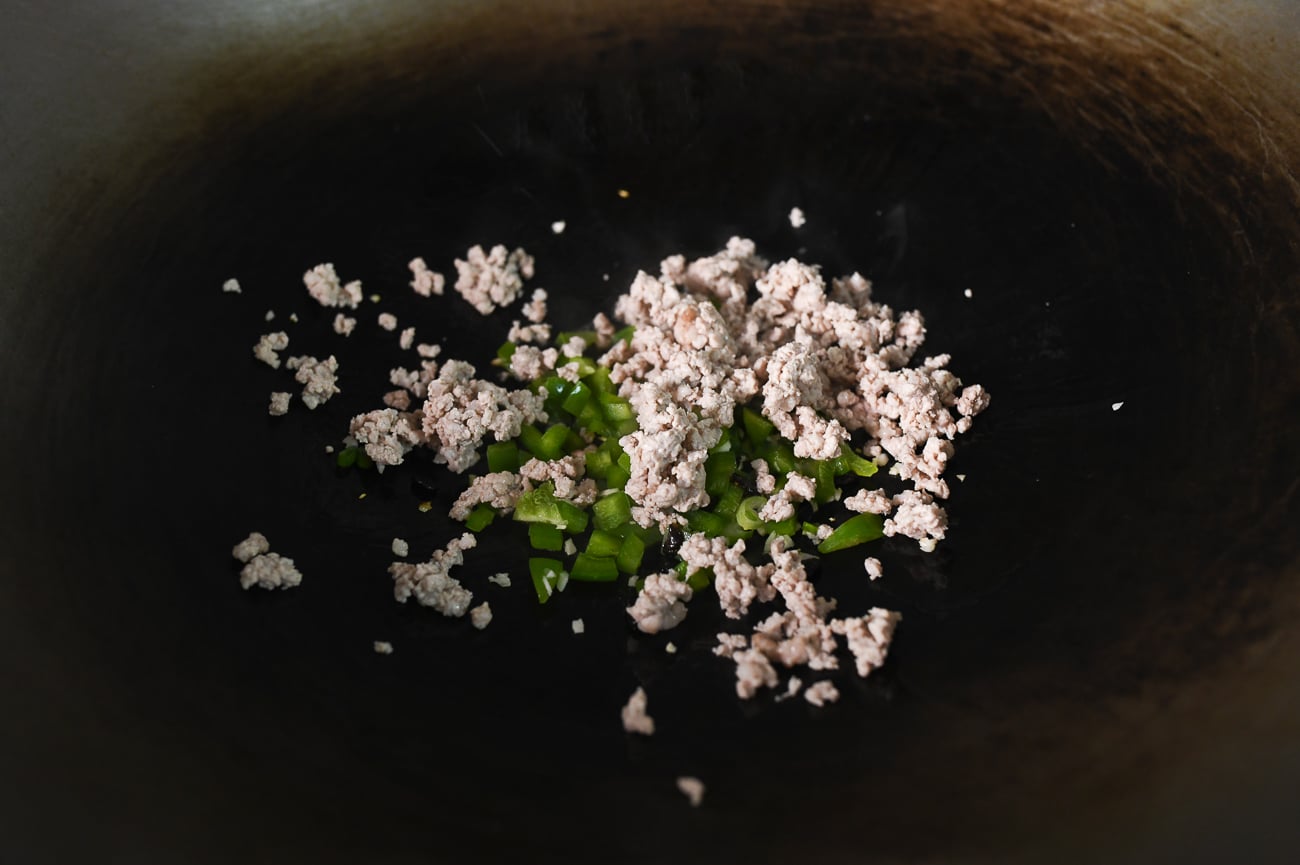 Bell pepper, ground pork, and other ingredients in wok