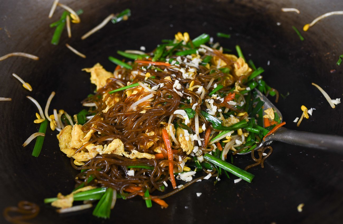 adding garlic to noodles, eggs, carrots, chives