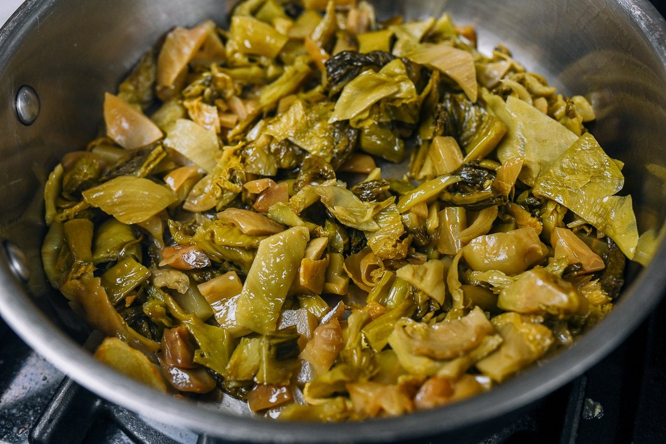 cooking chopped pickled mustard greens in stainless steel pan