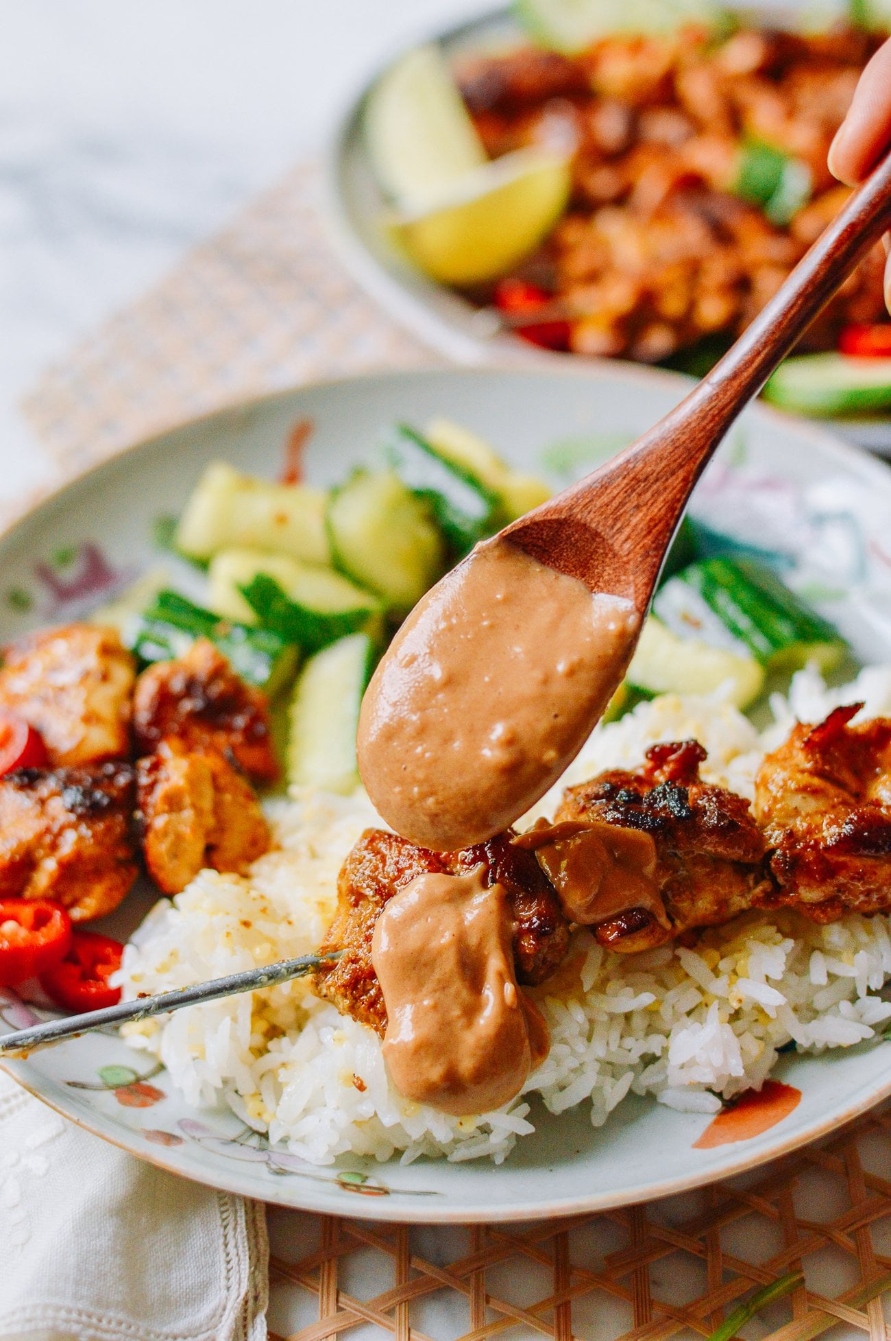 adding peanut sauce to chicken satay