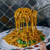 Lifting lo mein out of wok and transferring to serving platter