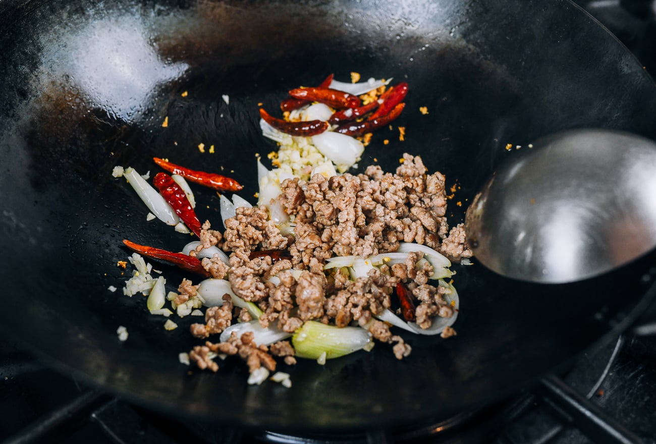 ginger, chilies, garlic, scallions, and cooked ground pork in wok