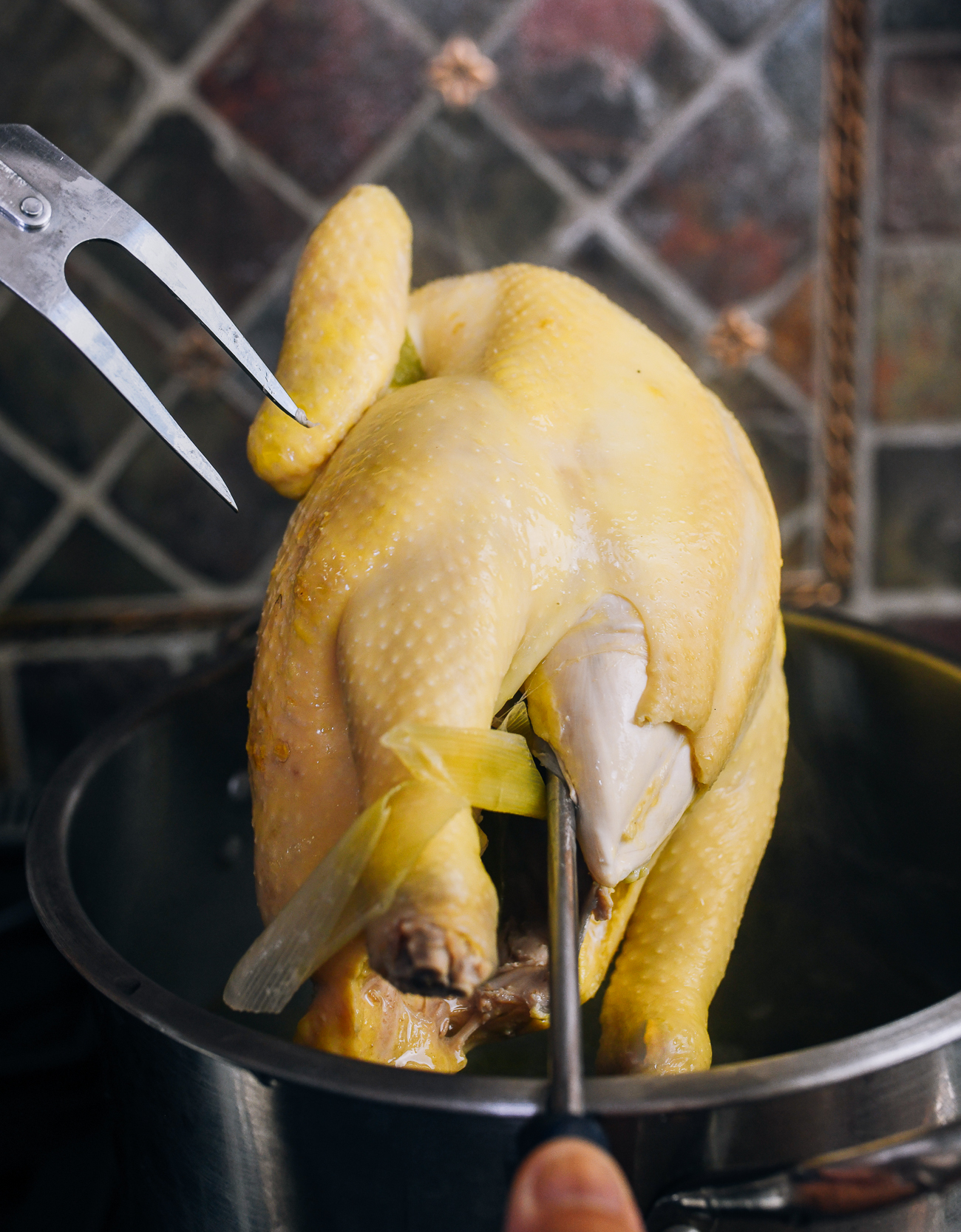 lifting poached chicken out of pot with fork