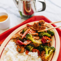 Picking up piece of Chinese takeout chicken with mixed vegetables with chopsticks