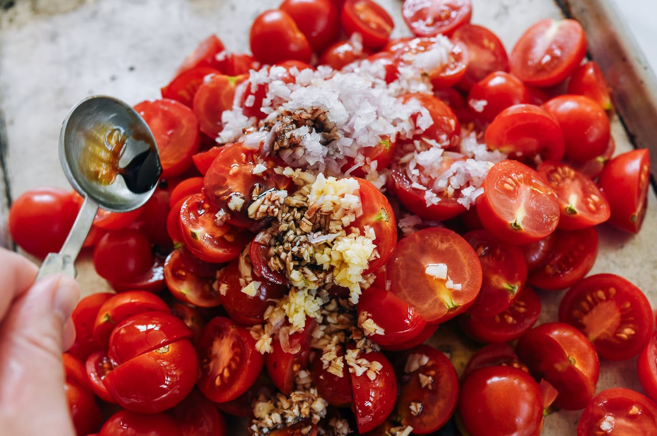tomato halves on sheet pan with garlic, shallot, balsamic