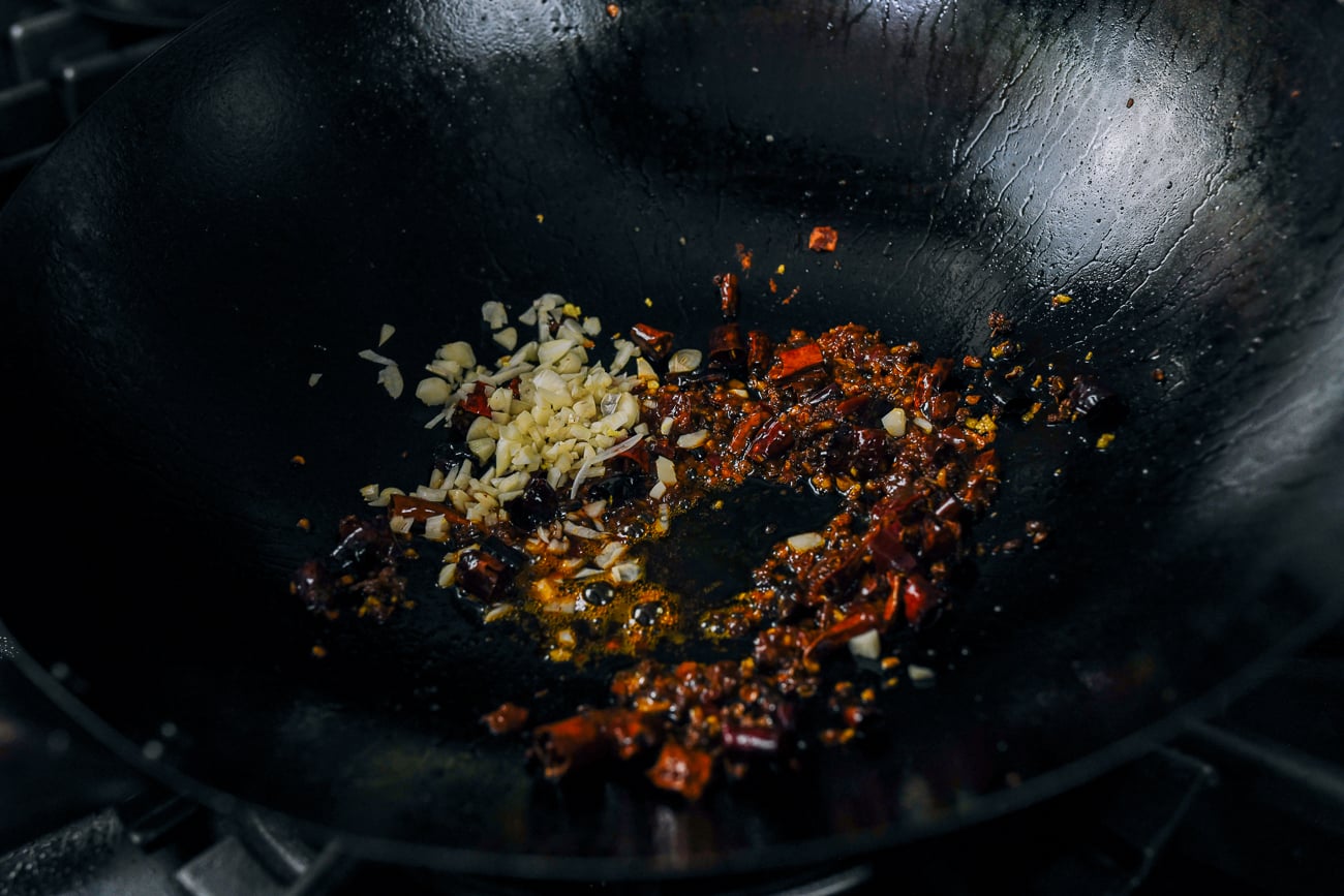 garlic, doubanjiang, dried chili, and Sichuan peppercorn in wok