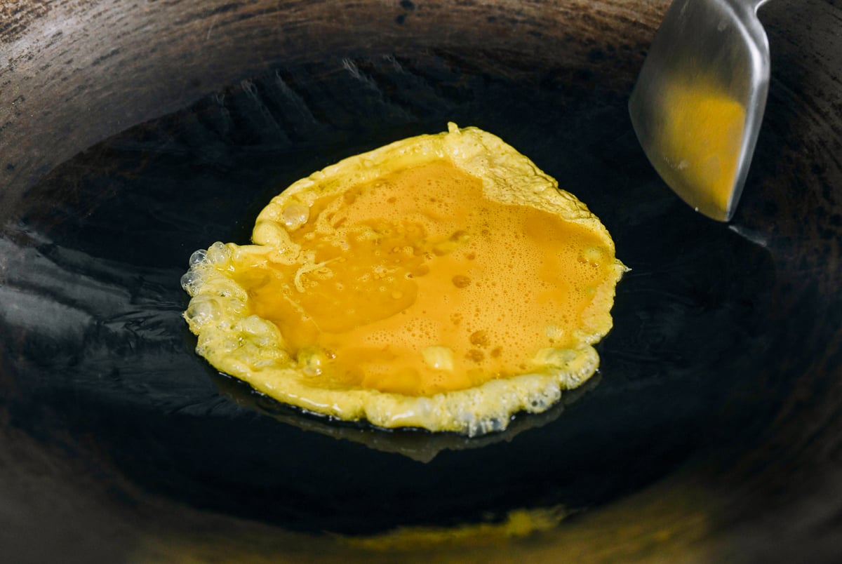 beaten eggs added to oil in a wok