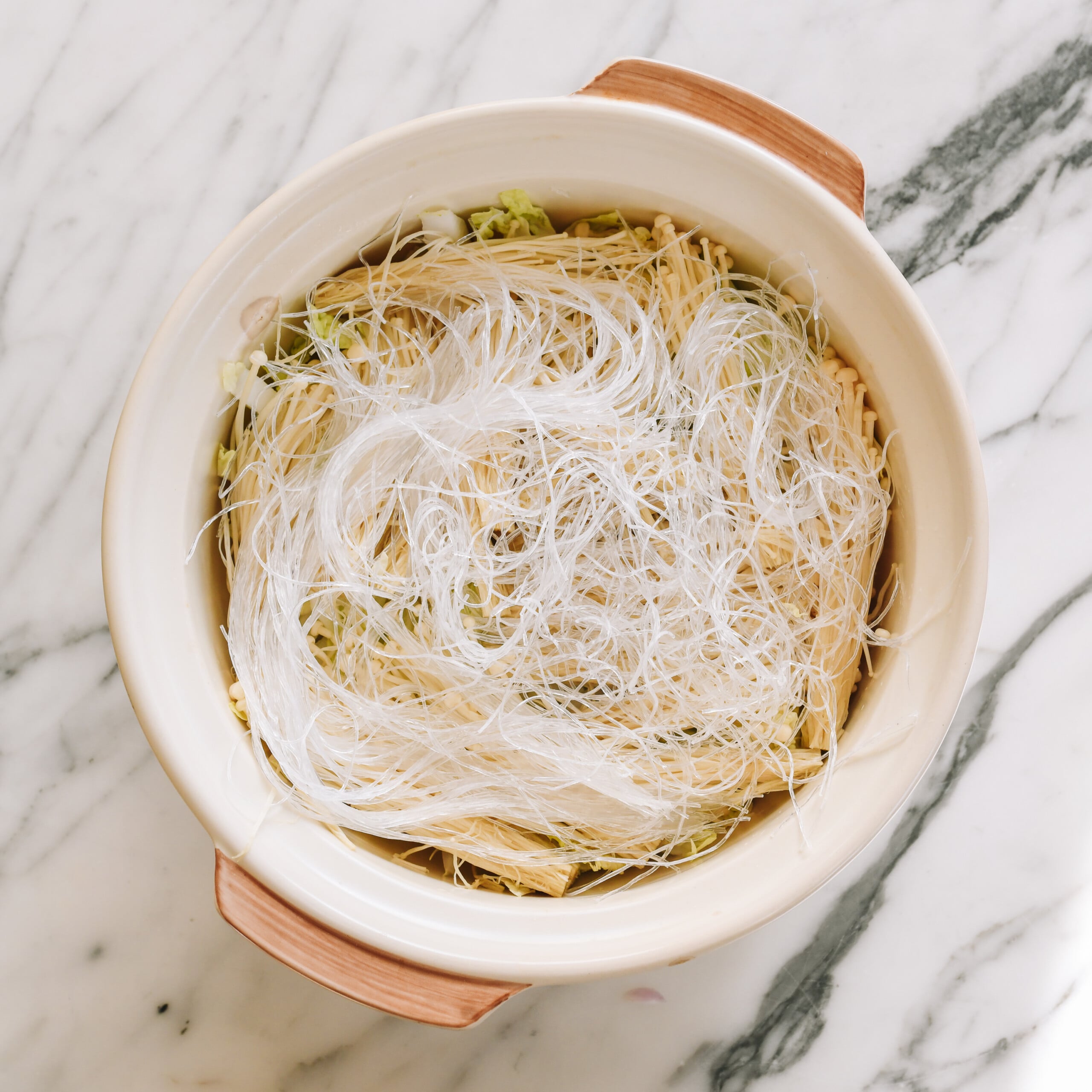 soaked glass noodles on top of vegetables in pot
