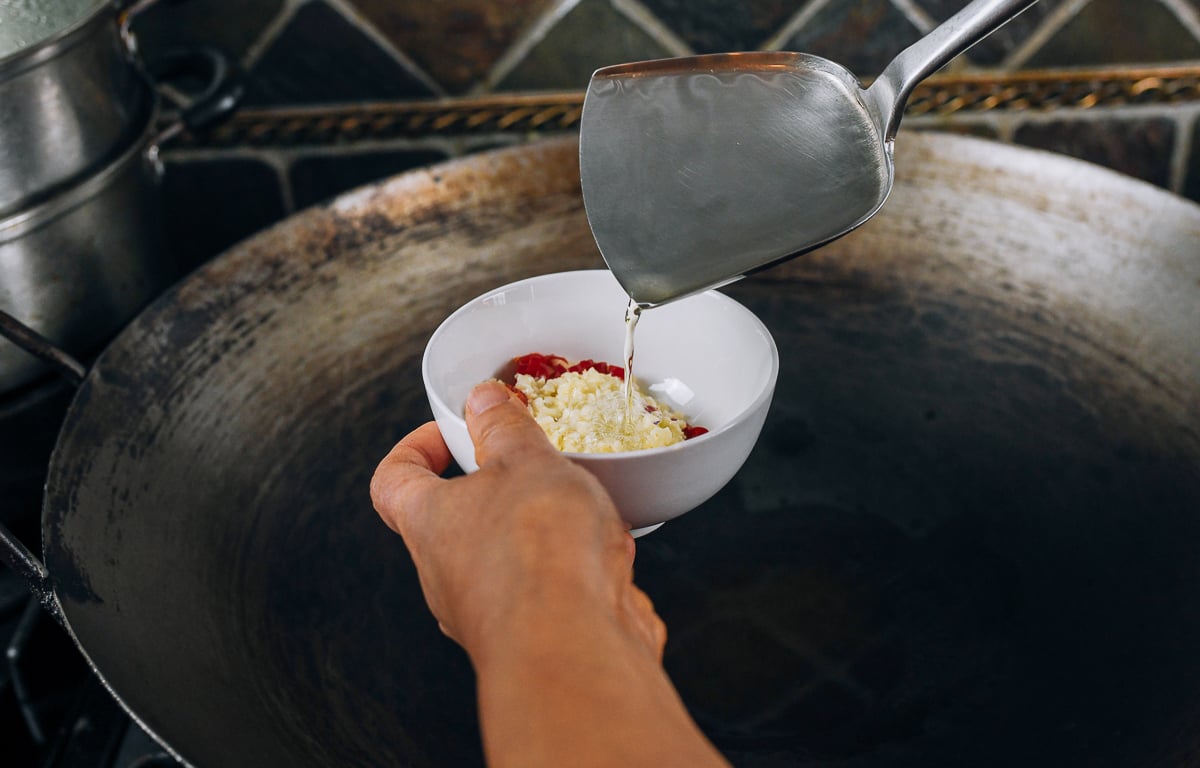 pouring hot oil over chilies and garlic