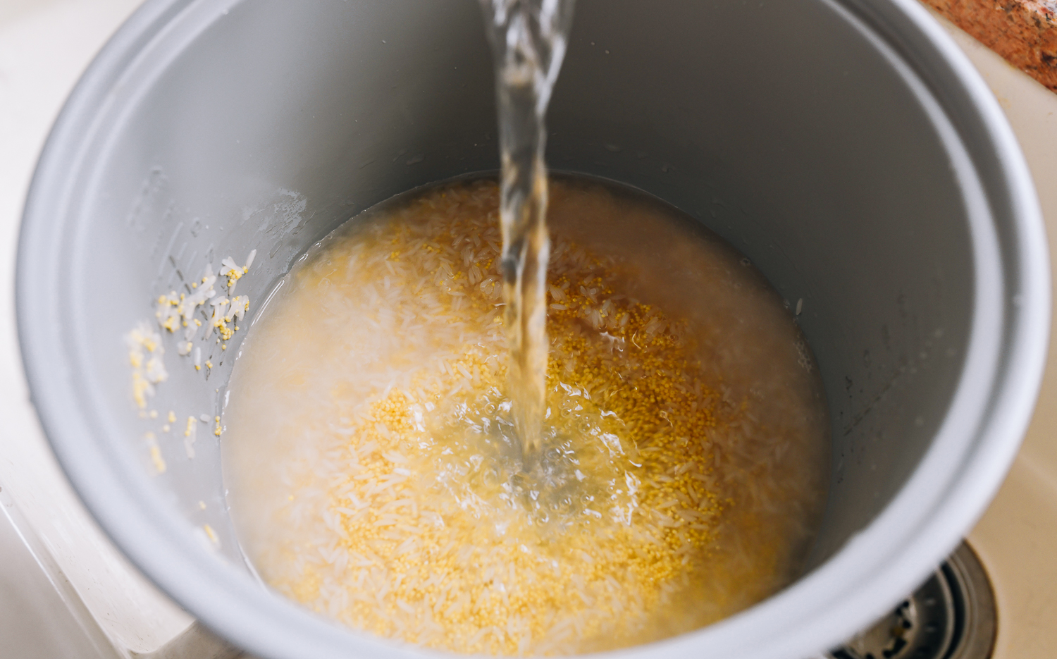 adding water to rice cooker pot with millet and rice