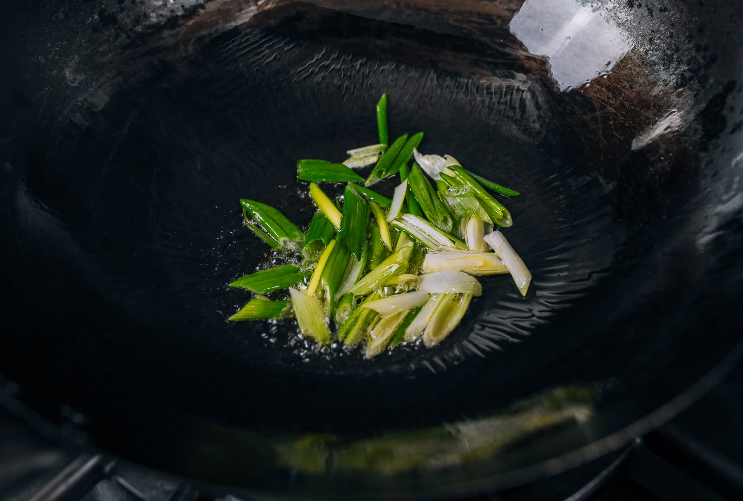 Frying scallions in oil in wok
