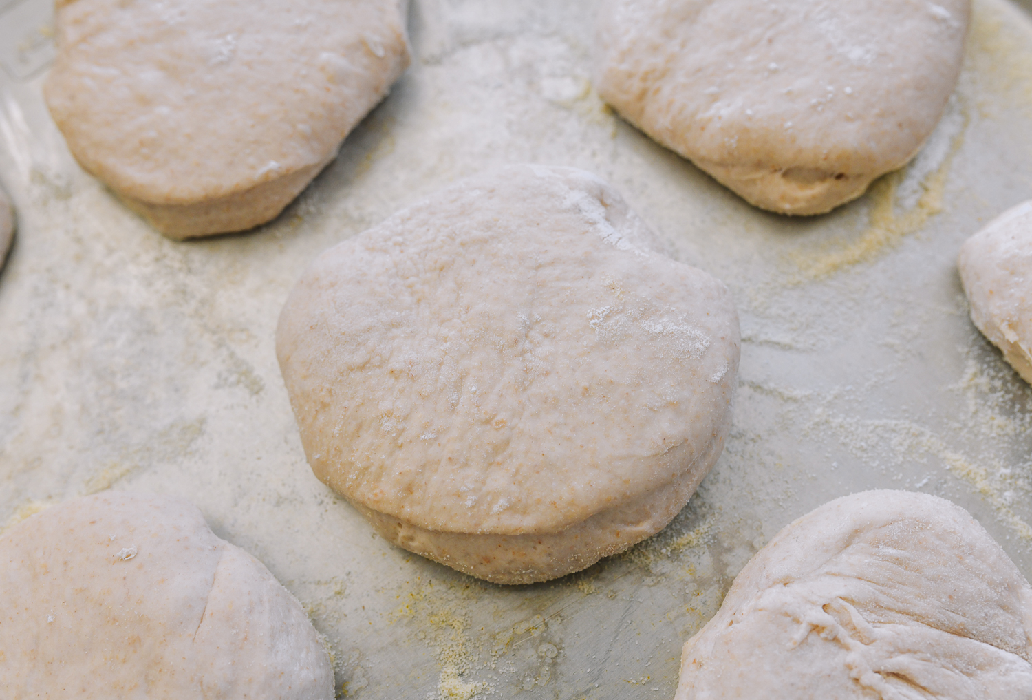 cut english muffin on semolina lined baking sheet