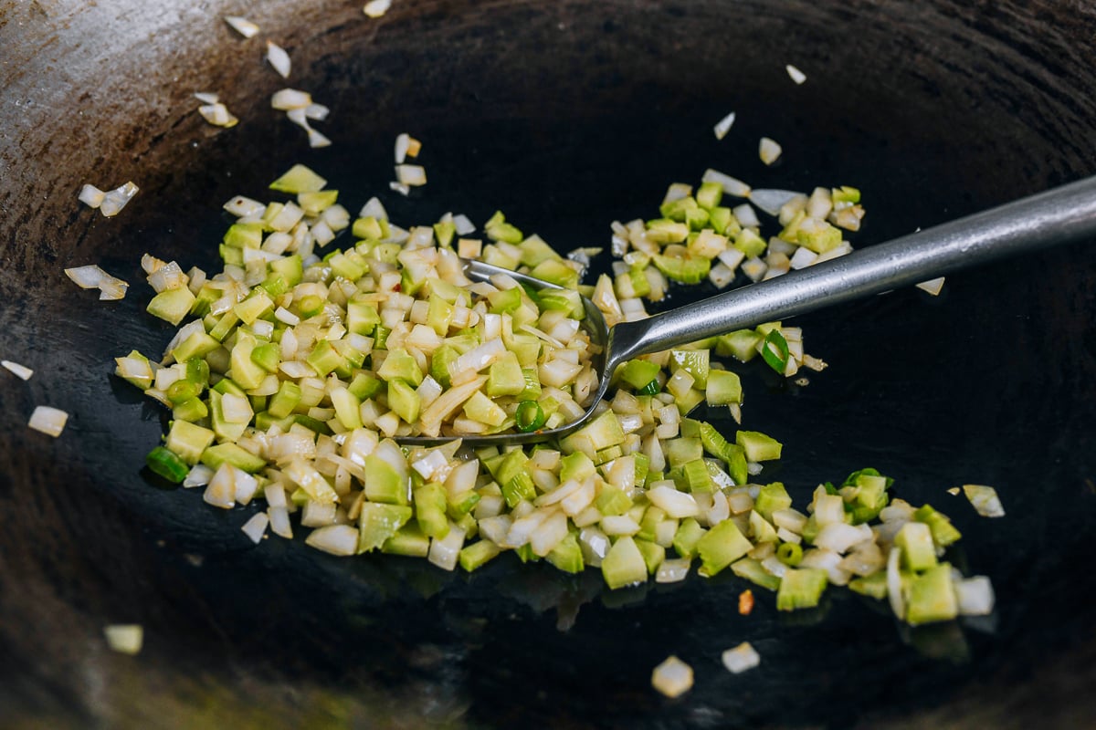 cooking diced onions and broccoli stems in wok