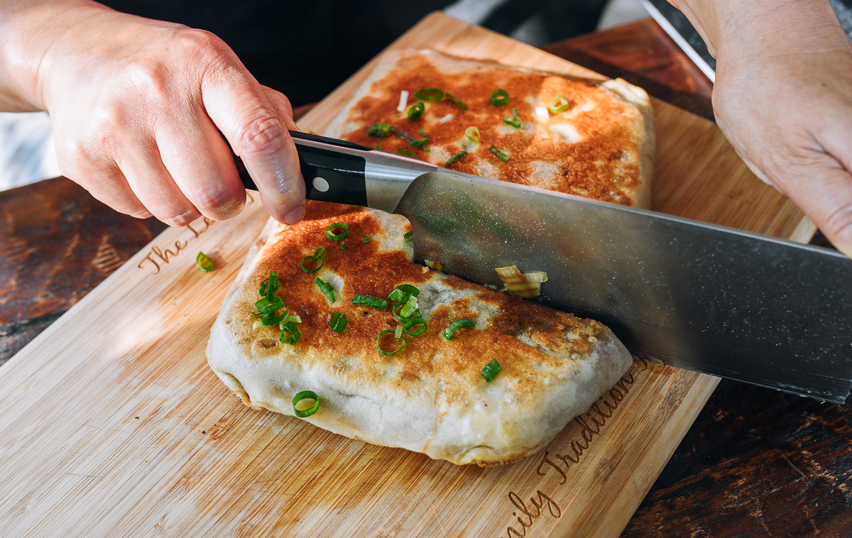cutting Chinese meat pie with a knife on cutting board
