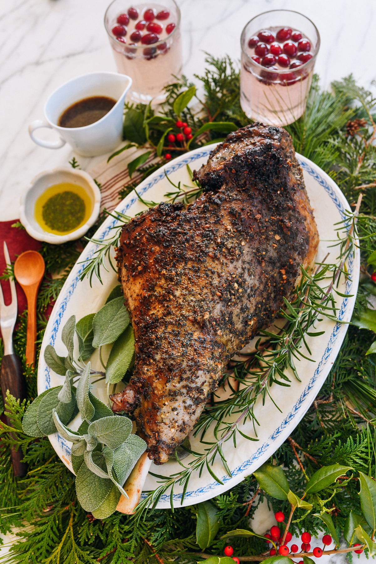 roast leg of lamb on serving platter with herbs