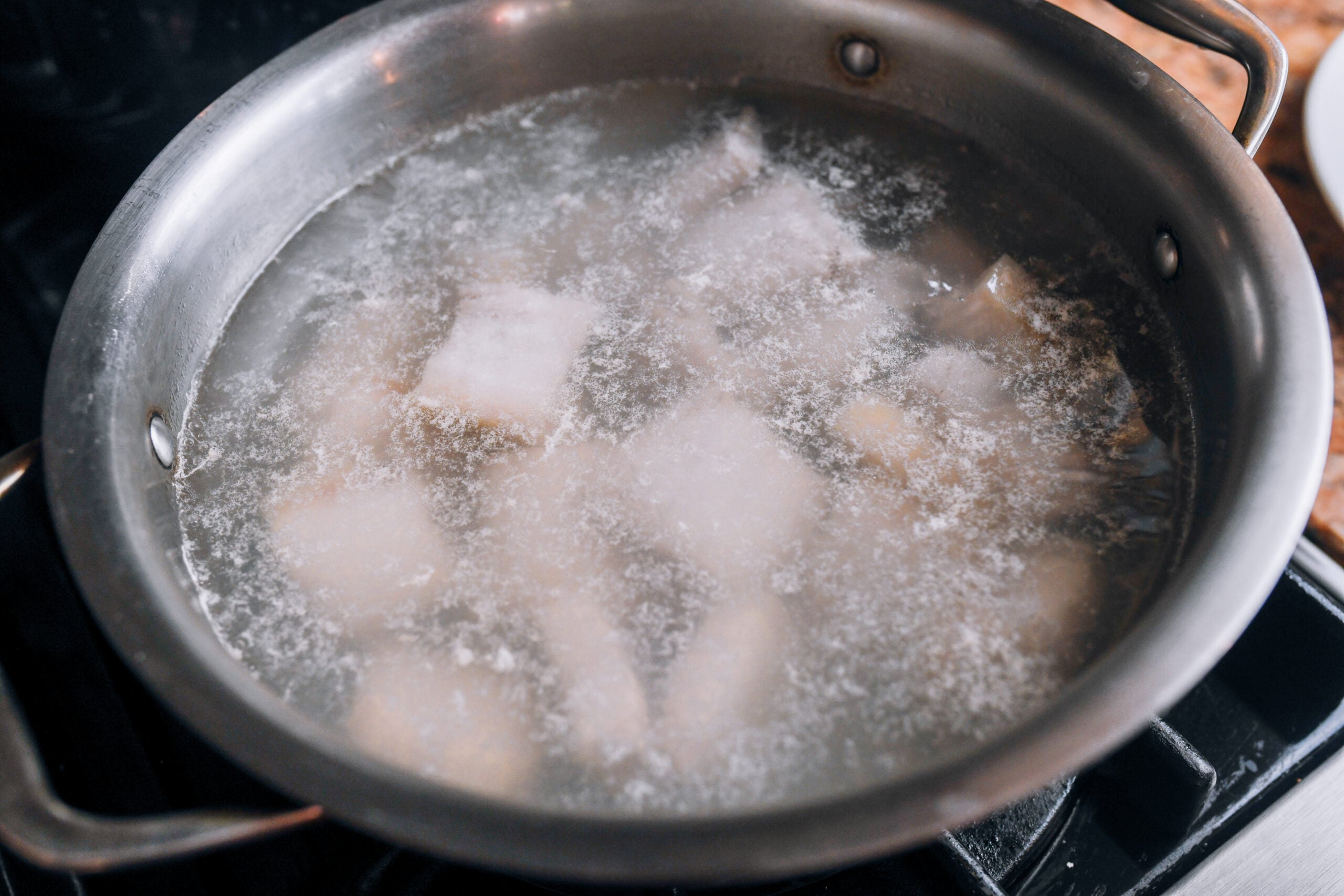 blanched pork belly pieces in pot of water