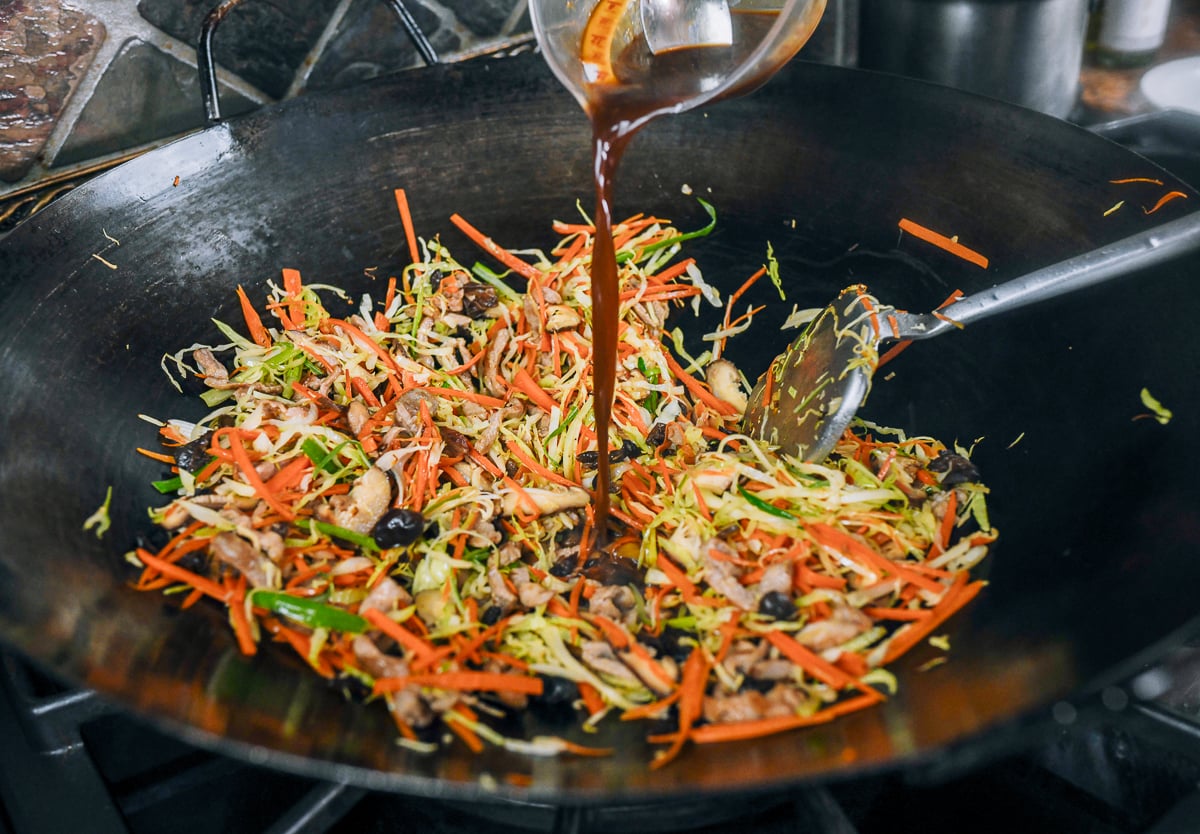 pouring seasoning mixture into moo shu pork stir-fry