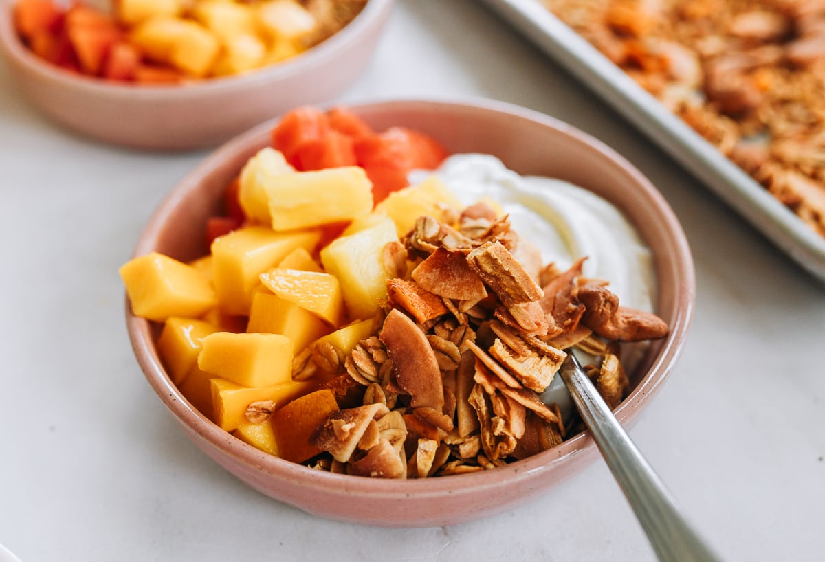 bowl of yogurt with tropical granola, mango, pineapple, and papaya