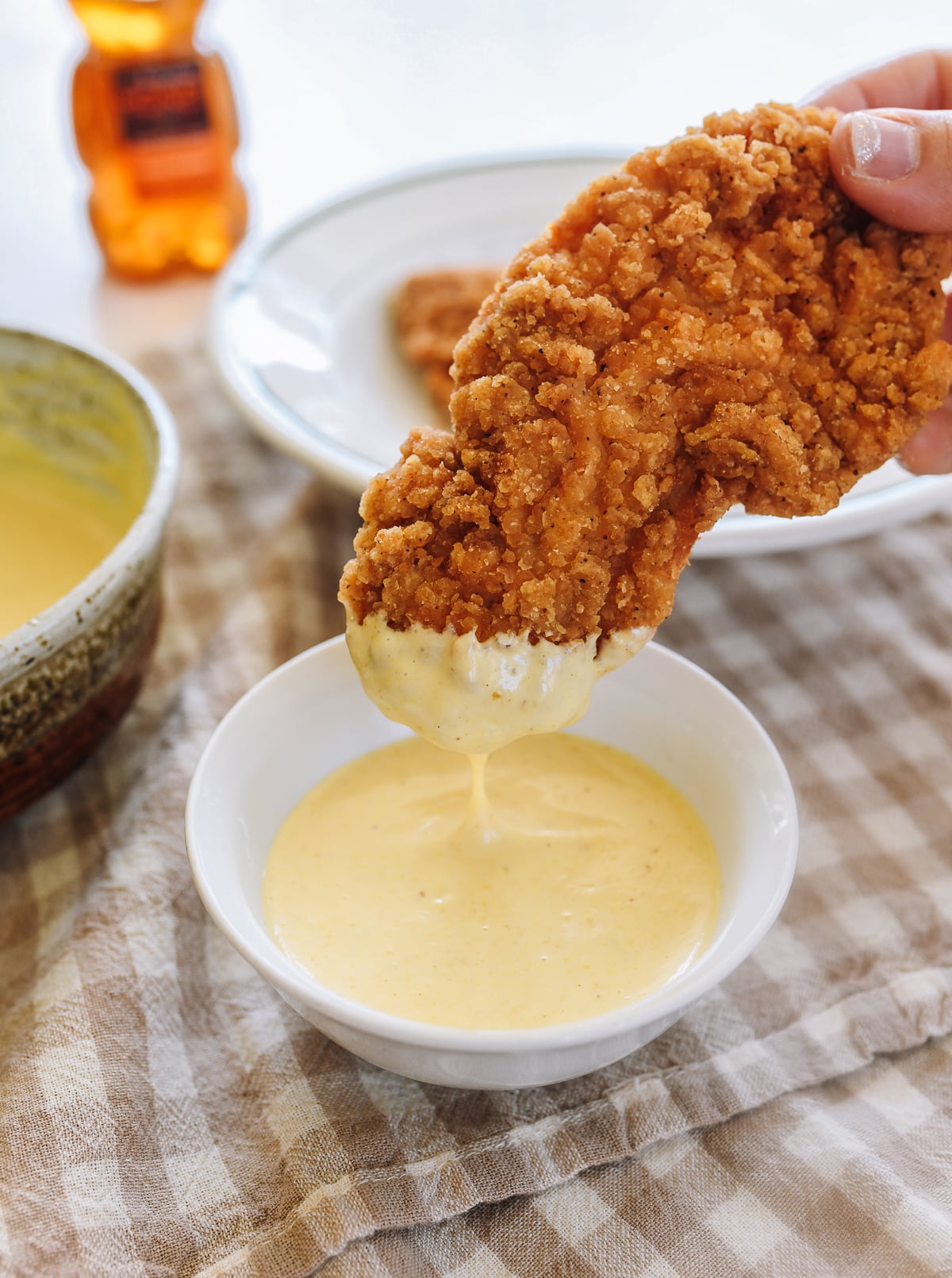 dipping chicken tender into homemade honey mustard dipping sauce