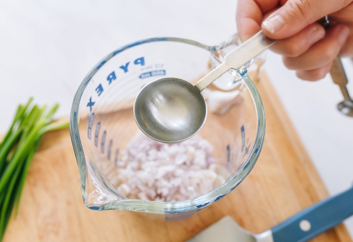 adding hot water to minced shallots in measuring cup
