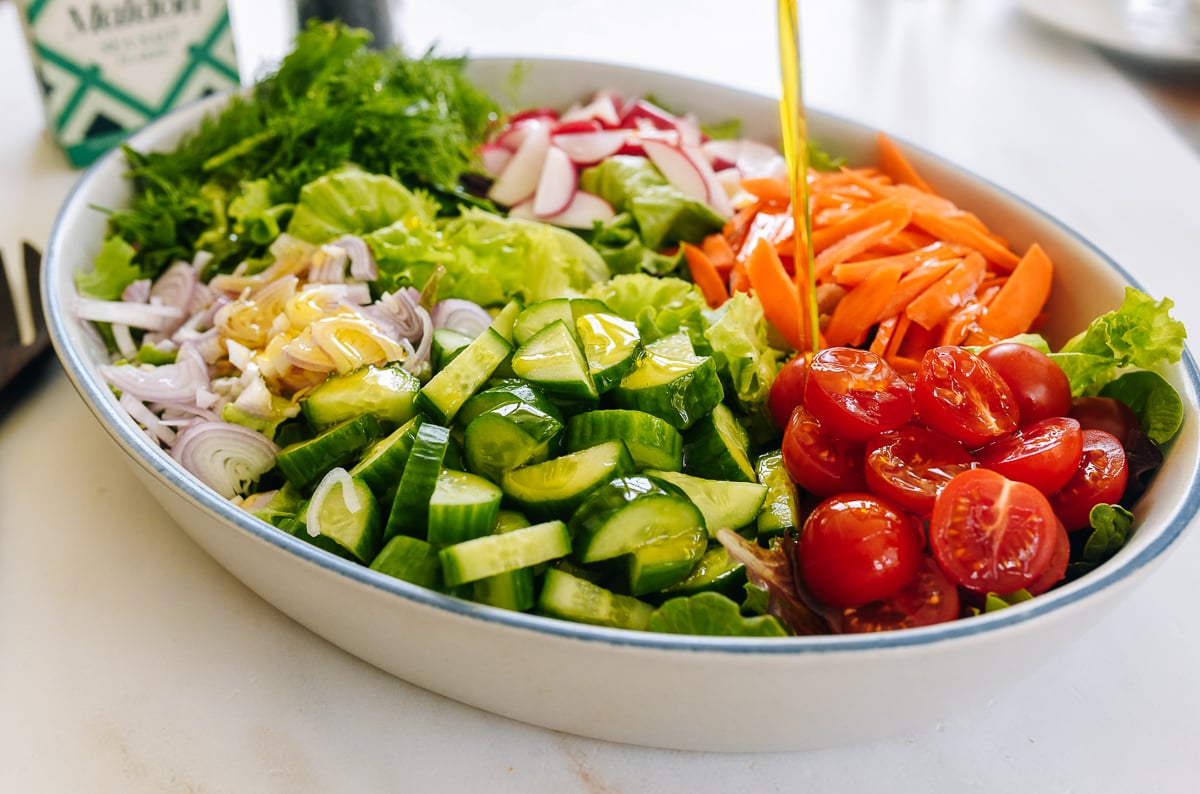pouring olive oil over salad