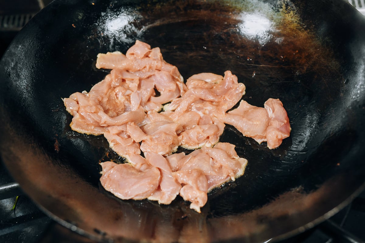 searing sliced chicken in wok