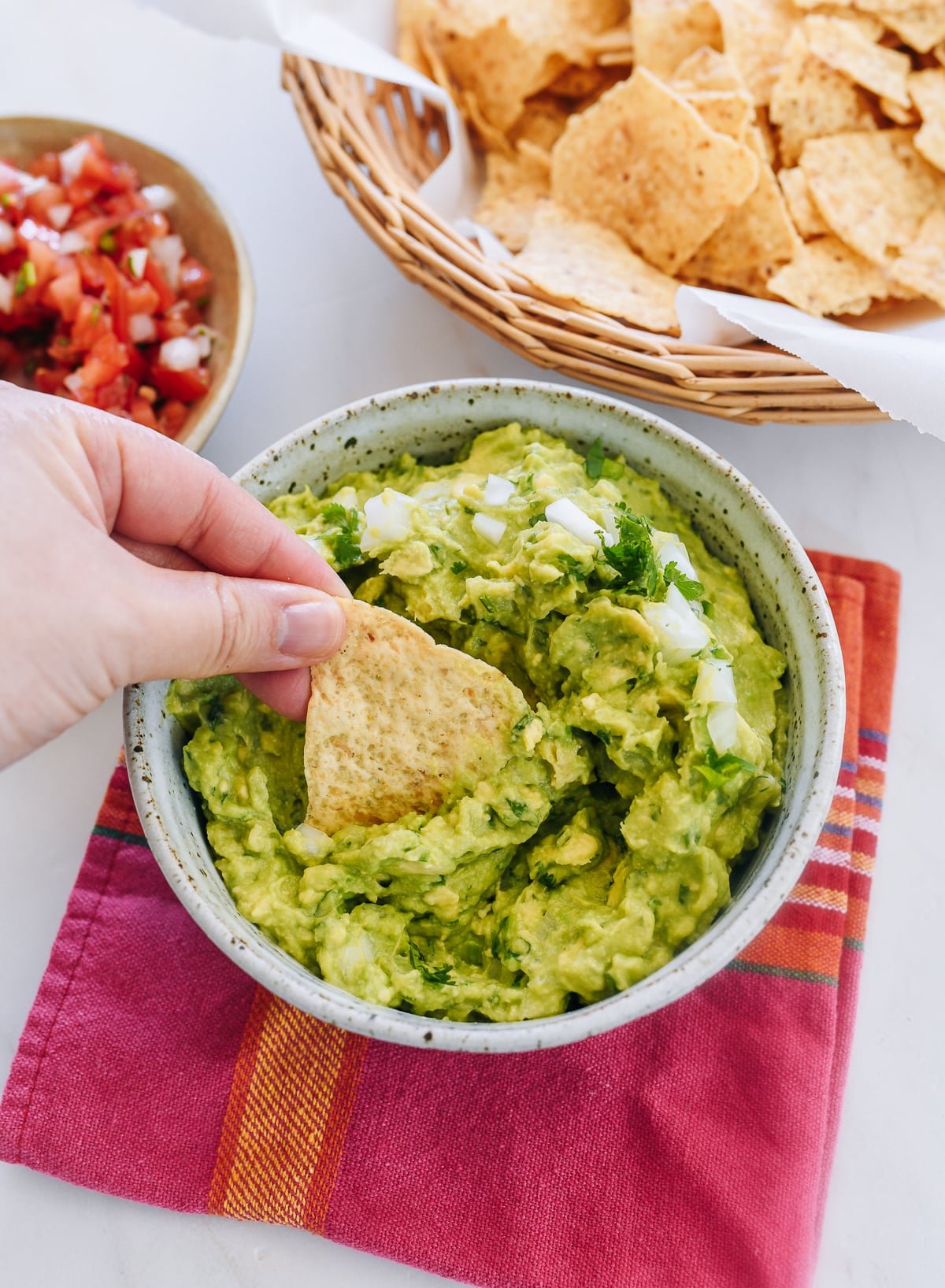 dipping tortilla chip into guacamole