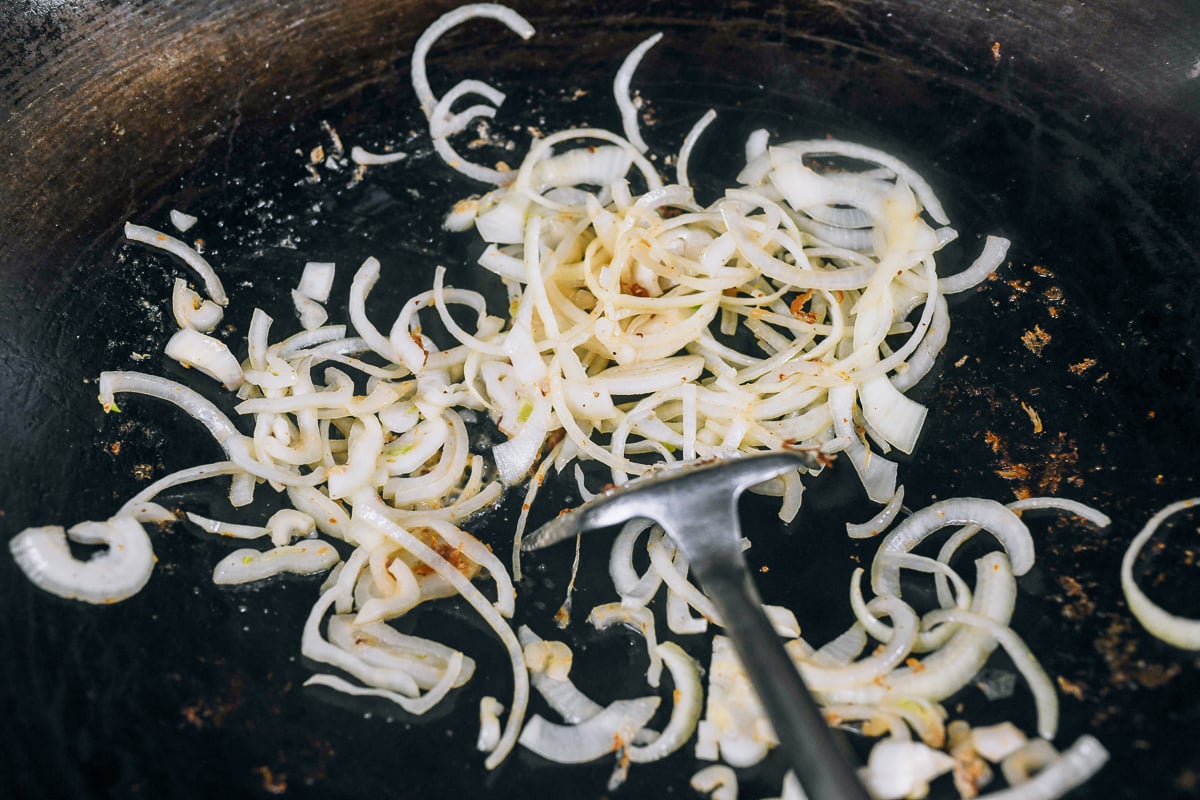 stir-frying sliced onions in wok