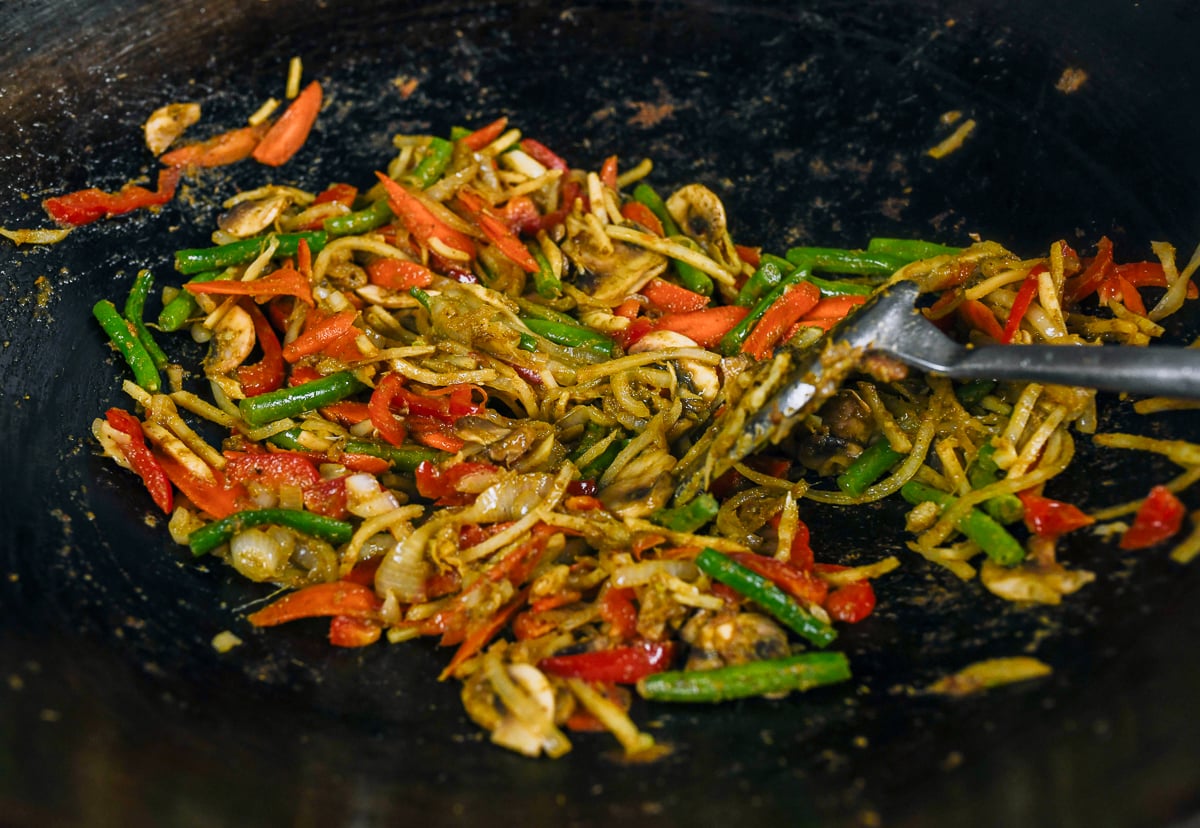 stir-frying vegetables with green curry paste