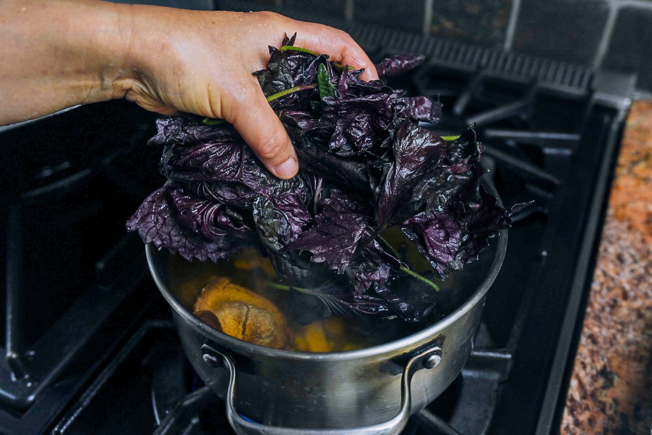 adding red shiso leaves to simmering water